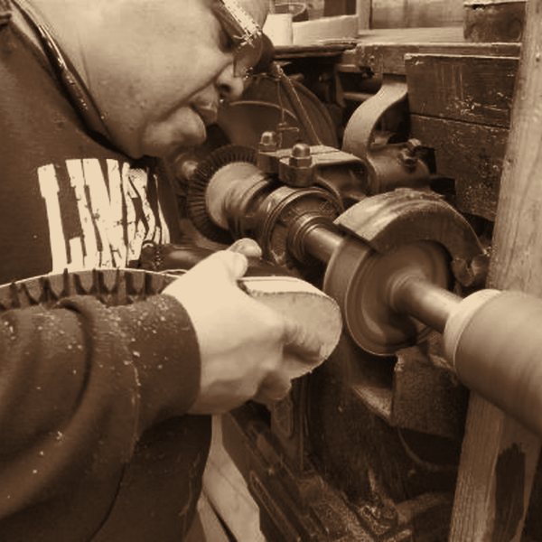An artisan finishing a boot sole at the workshop machine