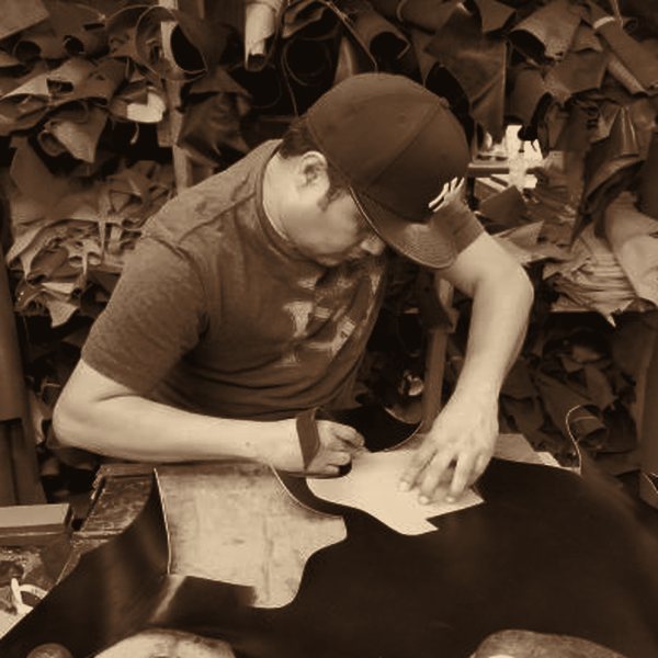 An artisan cutting a leather pattern by hand